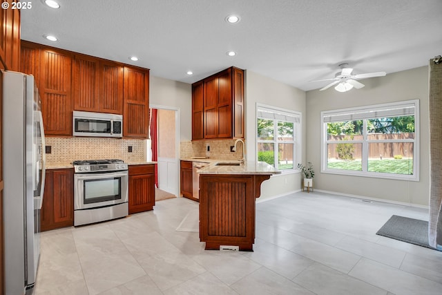 23836 SW Warbler Pl, Sherwood, OR 97140 - kitchen featuring appliances with stainless steel finishes, a peninsula, backsplash, a sink, and ceiling fan
