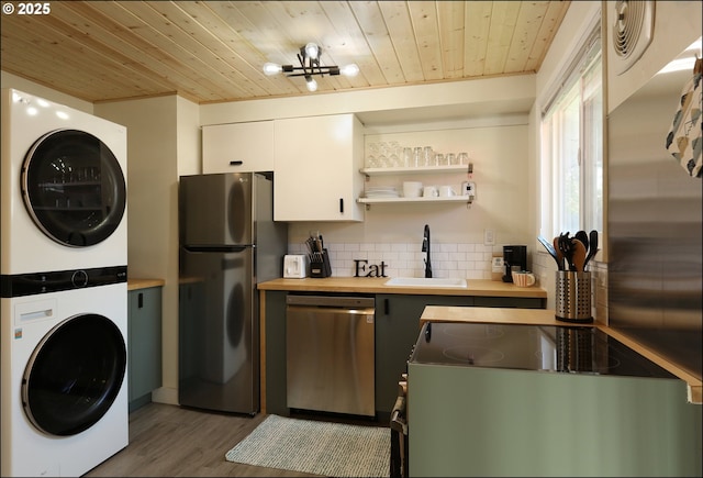 kitchen with refrigerator, stacked washer / dryer, dishwasher, sink, and white cabinets