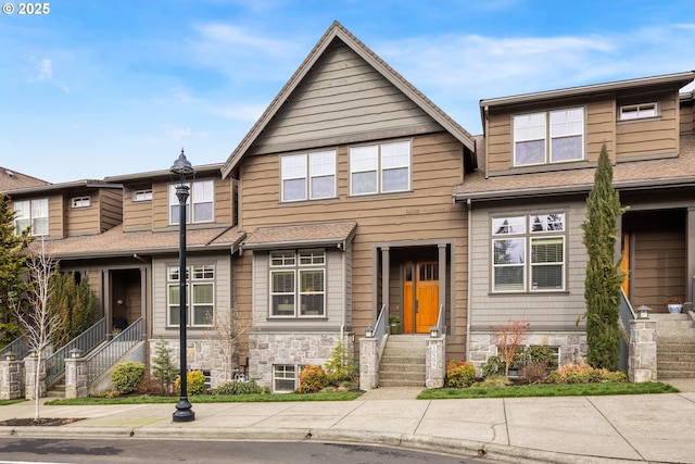 townhome / multi-family property featuring stone siding and a shingled roof