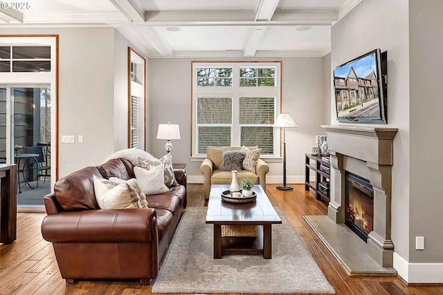 living room with baseboards, coffered ceiling, a glass covered fireplace, wood finished floors, and beamed ceiling