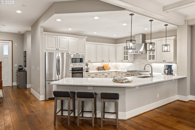 kitchen featuring a peninsula, appliances with stainless steel finishes, dark wood-type flooring, and a breakfast bar