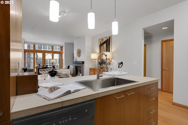 kitchen with sink, hanging light fixtures, black dishwasher, and light hardwood / wood-style floors