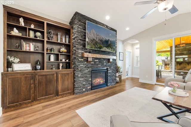 living room with light wood-style floors, arched walkways, ceiling fan, and vaulted ceiling