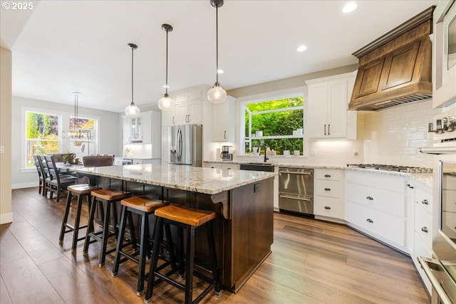 kitchen featuring white cabinets, appliances with stainless steel finishes, a center island, wood finished floors, and backsplash