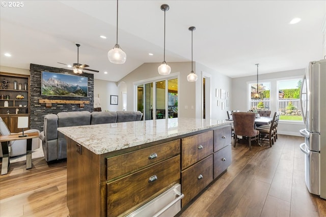 kitchen featuring freestanding refrigerator, hardwood / wood-style floors, light stone counters, a ceiling fan, and vaulted ceiling