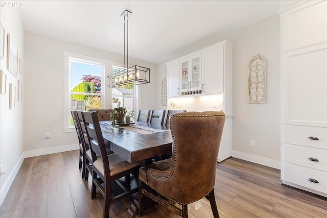 dining room featuring light wood-style floors, baseboards, and a chandelier
