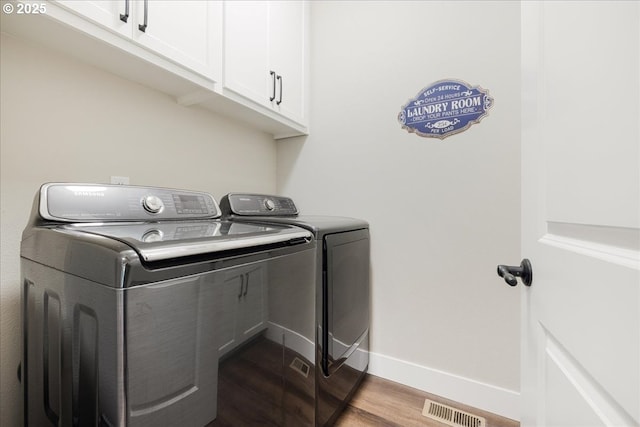 laundry area featuring visible vents, wood finished floors, washer and dryer, baseboards, and cabinet space