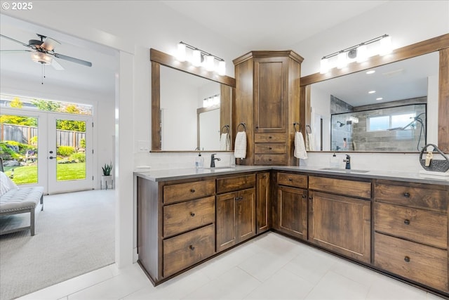 bathroom with double vanity, a sink, ceiling fan, and tiled shower
