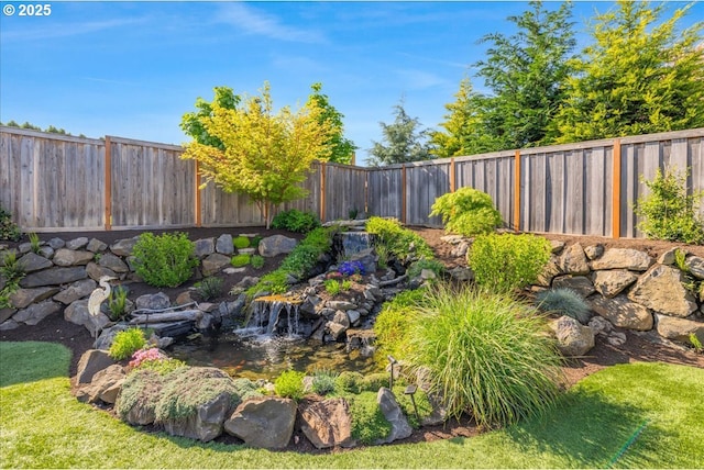 view of yard with a fenced backyard and a garden pond