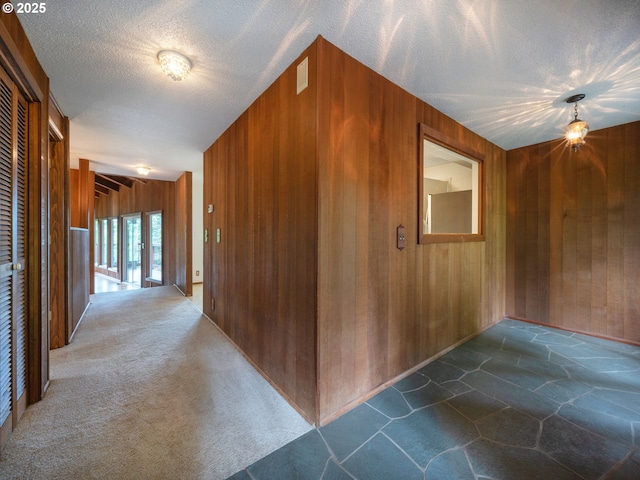 2830 Capital Dr, Eugene, OR 97403 - hallway featuring wood walls, dark stone finish flooring, and a textured ceiling
