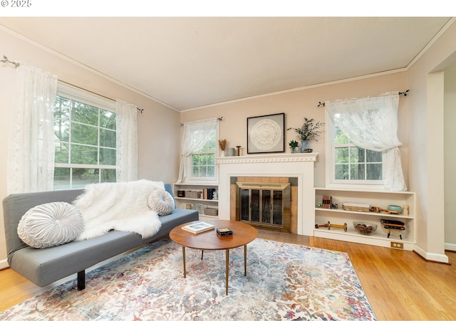 living room with a fireplace with flush hearth, crown molding, and wood finished floors