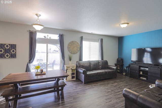 living room featuring dark wood-type flooring, a wealth of natural light, and a textured ceiling