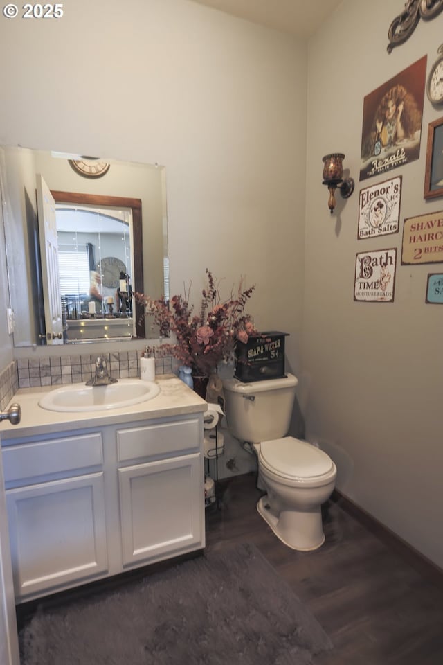 bathroom with wood finished floors, vanity, toilet, and baseboards