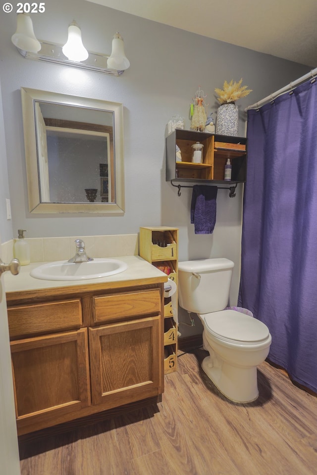 full bathroom with a shower with shower curtain, vanity, toilet, and wood finished floors