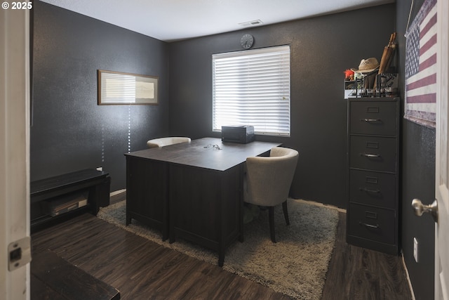 home office with a textured wall, wood finished floors, and visible vents