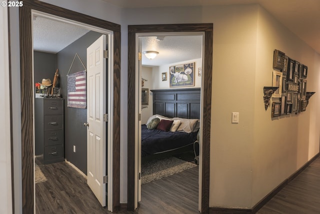 hall with baseboards, dark wood-type flooring, and a textured ceiling