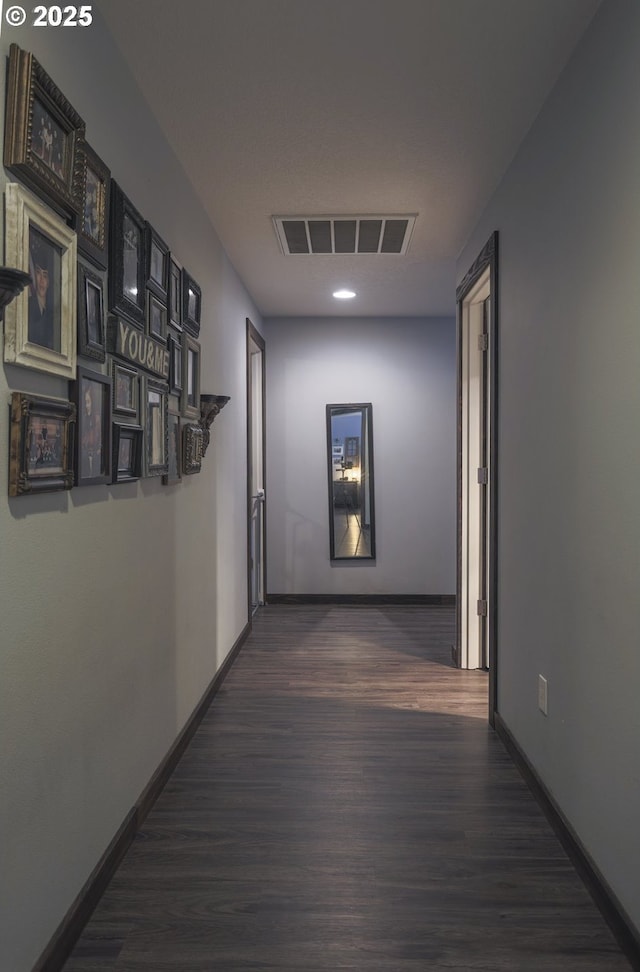 corridor with dark wood-style flooring, visible vents, and baseboards