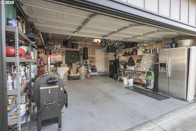 garage featuring a garage door opener, stainless steel fridge with ice dispenser, and a workshop area