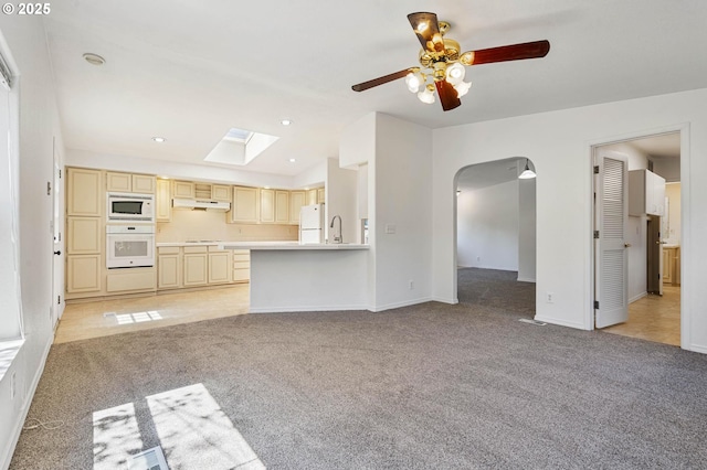 9341 N Pier Park Pl, Portland, OR 97203 - unfurnished living room featuring light colored carpet, a skylight, ceiling fan, vaulted ceiling, and arched walkways