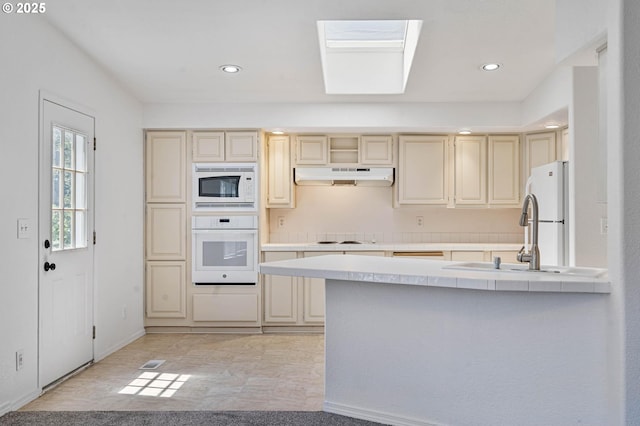 9341 N Pier Park Pl, Portland, OR 97203 - kitchen with white appliances, under cabinet range hood, cream cabinets, a peninsula, and recessed lighting