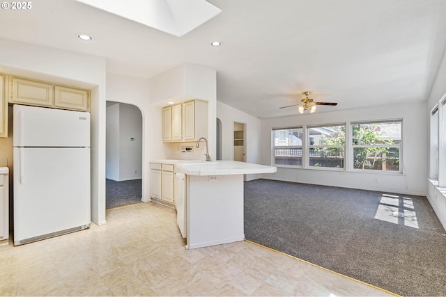 9341 N Pier Park Pl, Portland, OR 97203 - kitchen with freestanding refrigerator, arched walkways, light colored carpet, a skylight, and recessed lighting