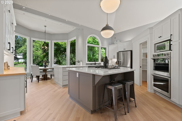 17595 Kelok Rd, Lake Oswego, OR 97034 - kitchen featuring stainless steel appliances, a chandelier, light wood-style floors, a kitchen island, and white cabinetry