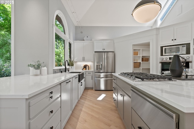 17595 Kelok Rd, Lake Oswego, OR 97034 - kitchen with stainless steel appliances, a sink, lofted ceiling, light stone countertops, and light wood finished floors