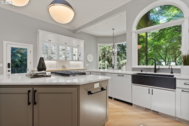 17595 Kelok Rd, Lake Oswego, OR 97034 - kitchen with a sink, white cabinets, light wood-style flooring, a center island, and hanging light fixtures