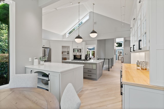 17595 Kelok Rd, Lake Oswego, OR 97034 - kitchen with high vaulted ceiling, appliances with stainless steel finishes, light wood finished floors, light countertops, and a center island