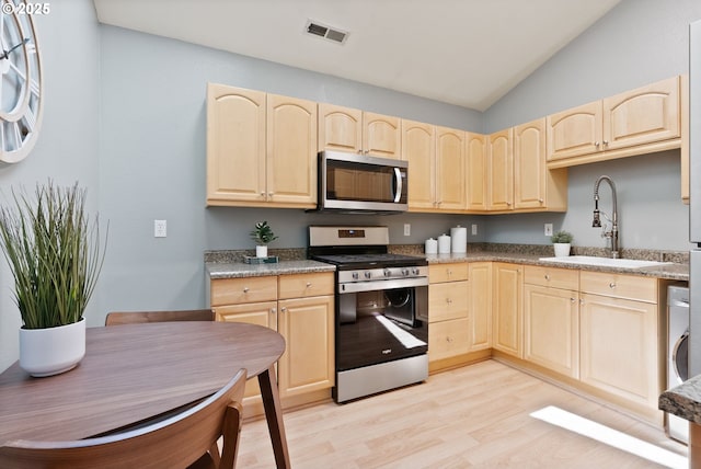 17595 Kelok Rd, Lake Oswego, OR 97034 - kitchen featuring appliances with stainless steel finishes, light brown cabinets, a sink, light wood-type flooring, and lofted ceiling