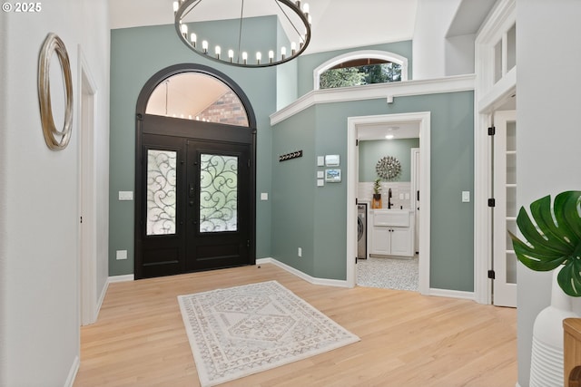 17595 Kelok Rd, Lake Oswego, OR 97034 - entryway featuring washer / clothes dryer, wood finished floors, a chandelier, baseboards, and a high ceiling