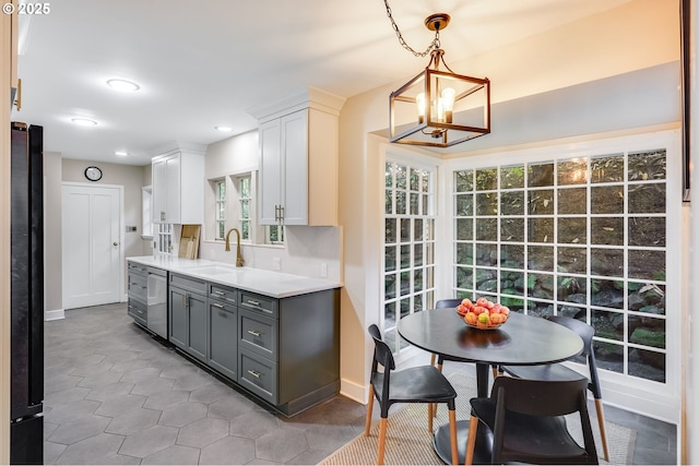 kitchen with light countertops, gray cabinetry, freestanding refrigerator, a sink, and dishwasher