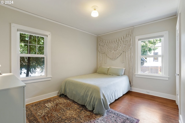 bedroom with crown molding, wood finished floors, and baseboards