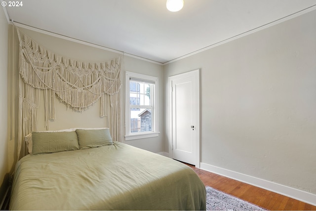 bedroom with ornamental molding, wood finished floors, and baseboards