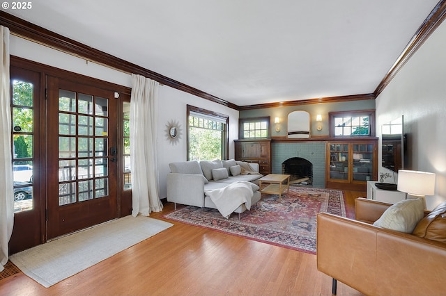living room with a brick fireplace, ornamental molding, and wood finished floors