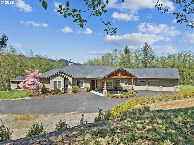 view of front of house featuring an attached garage, a chimney, driveway, and stone siding