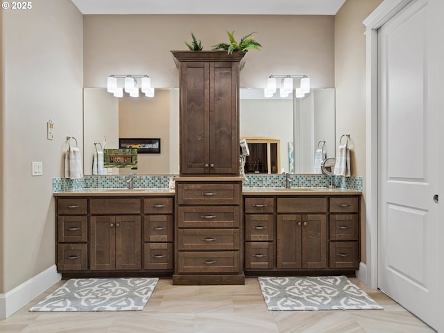 bathroom with a sink, baseboards, tasteful backsplash, and double vanity