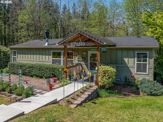 view of front of house featuring board and batten siding, a shingled roof, and a front lawn