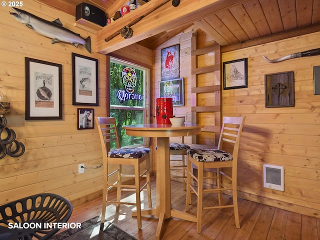 dining space featuring visible vents, wood ceiling, wooden walls, and hardwood / wood-style floors