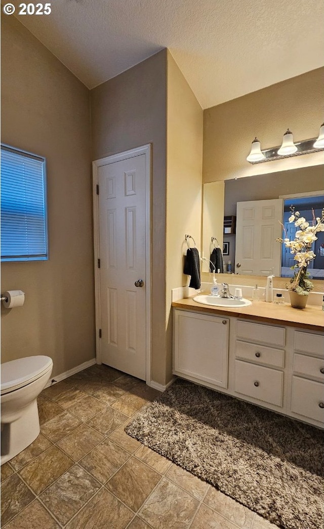 bathroom with vanity, toilet, and a textured ceiling