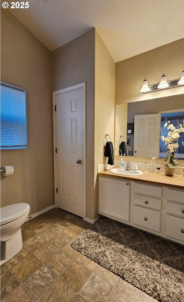 6004 Quartz Ave, Springfield, OR 97478 - bathroom featuring vanity, toilet, stone finish floors, and baseboards