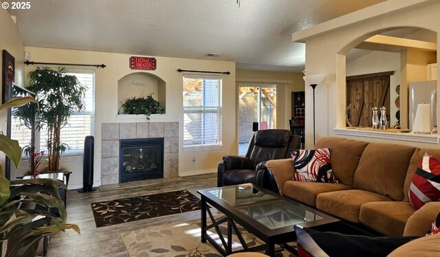 6004 Quartz Ave, Springfield, OR 97478 - living room featuring plenty of natural light, baseboards, a tiled fireplace, a textured ceiling, and wood finished floors