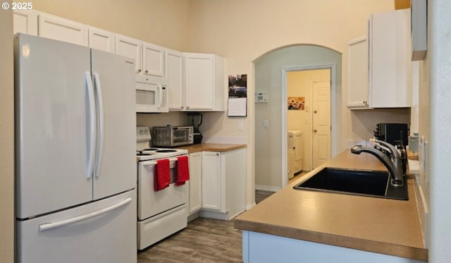 kitchen with dark hardwood / wood-style floors, sink, white cabinets, and white appliances