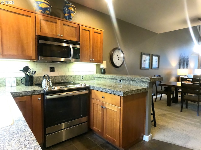 kitchen with tasteful backsplash, dark carpet, kitchen peninsula, and appliances with stainless steel finishes