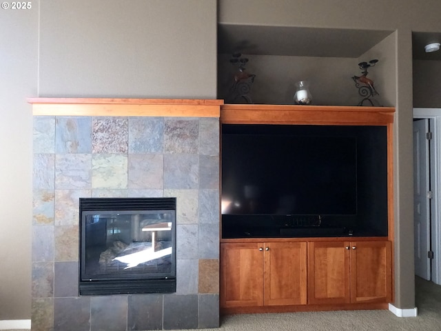 interior details featuring a tiled fireplace and carpet floors