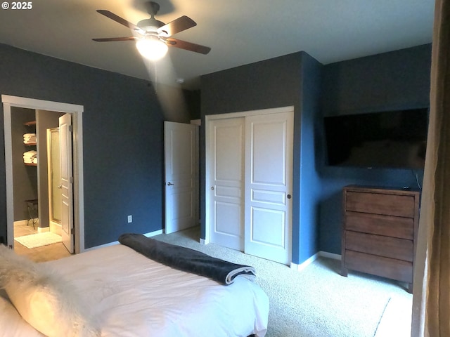 carpeted bedroom with ensuite bathroom, ceiling fan, and a closet