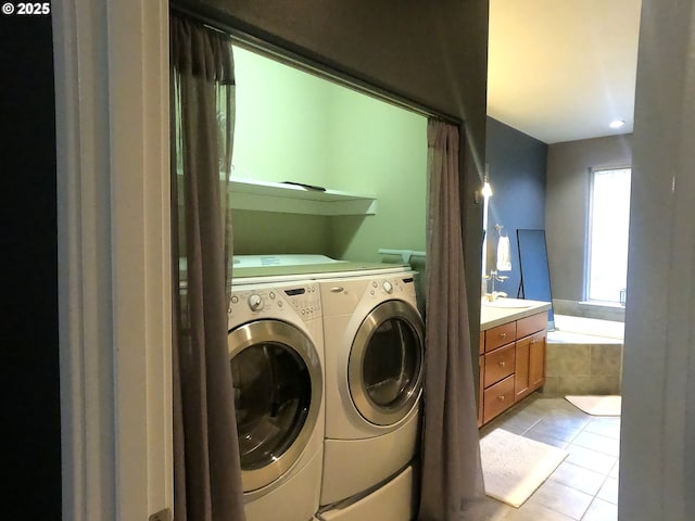 clothes washing area with separate washer and dryer, sink, and light tile patterned floors