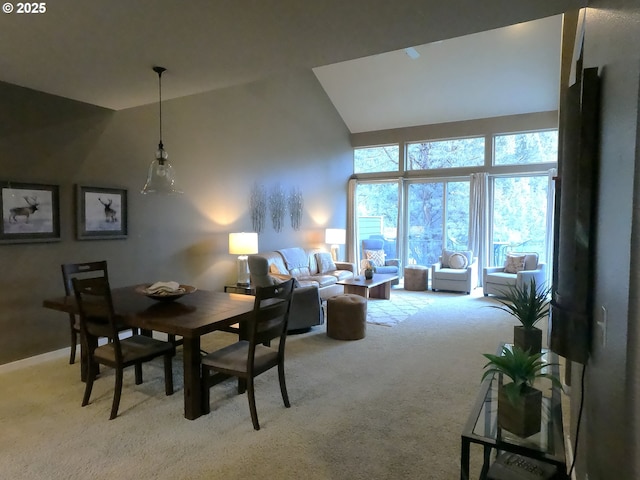 carpeted dining space with high vaulted ceiling