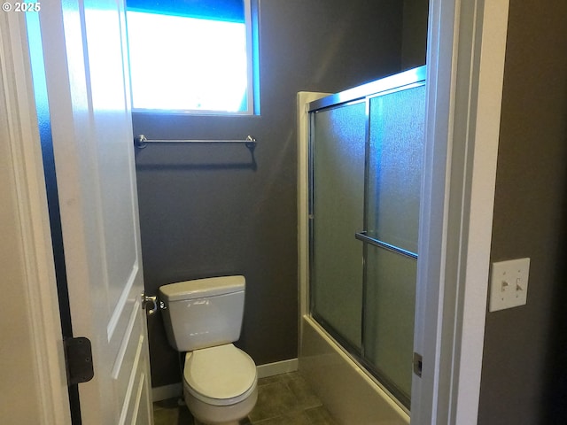 bathroom featuring tile patterned flooring, enclosed tub / shower combo, and toilet