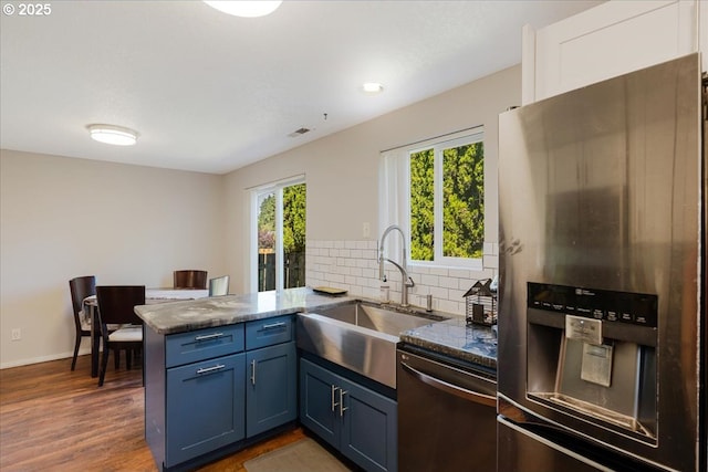 20657 SW Nantucket Ln, Beaverton, OR 97006 - kitchen featuring stainless steel appliances, a peninsula, decorative backsplash, a sink, and dark stone countertops
